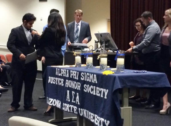New members receive pins during the Alpha Phi Sigma induction ceremony
