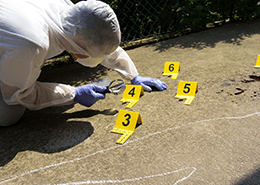 Crime scene investigator peering through magnifying glass at evidence