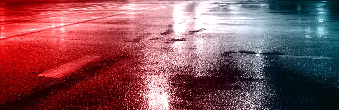 A wet street reflecting red and blue police lights
