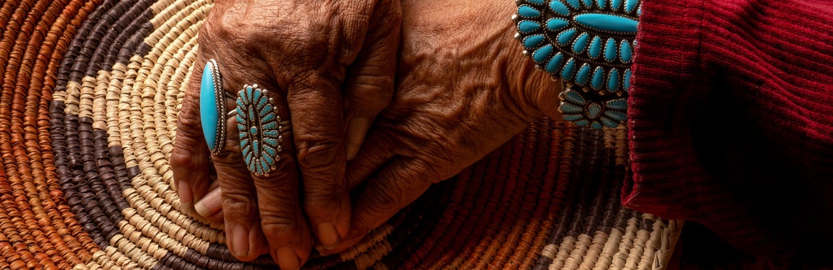 Research on Violent Victimization (ROVV) Lab - dark-skinned hand with turquoise rings against a woven placemat