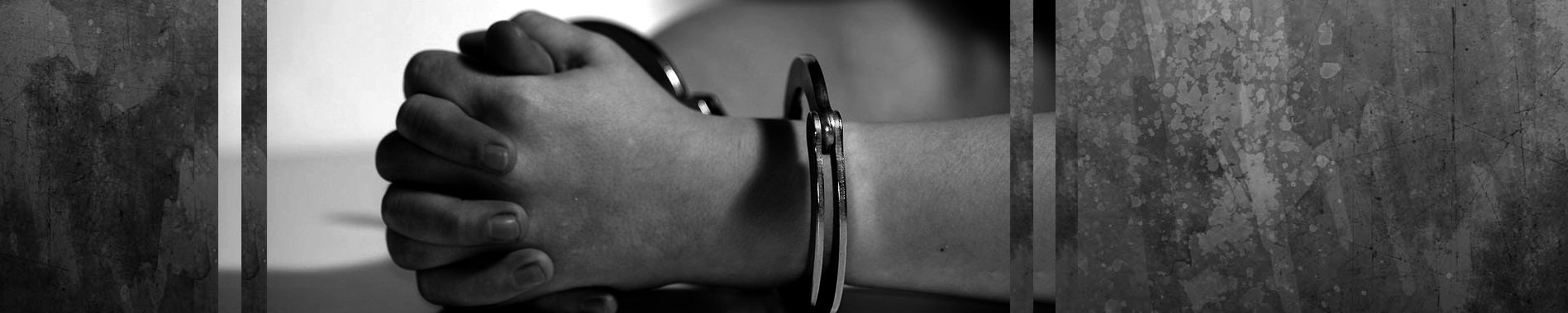 black and white photo of hands clasped together in handcuffs 